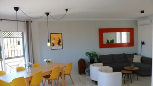 Ein modernes Wohnzimmer mit Essbereich, einem grauen Sofa und einem spiegel mit rotem Rahmen.