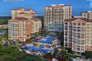 A high-rise hotel with multiple balconies, a central swimming pool, and surrounding greenery. - Marriott Oceanwatch Myrtle Beach 2 Bdr 6/18-6/25 (Myrtle Beach)