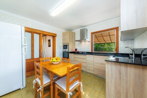 Una cocina compacta con una mesa de comedor de madera, un microondas y un lavamanos.