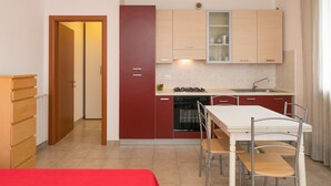 Una cocina compacta con comedor, estufa, lavaplatos y pileta.