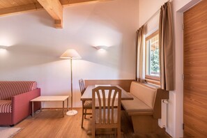 Ein gemütlicher Raum mit einem Holztisch, einer Bank, einem Sofa und einer Lampe.