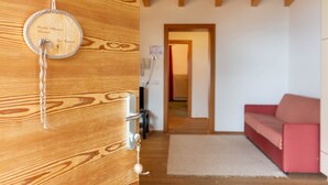 Eine Holztür mit einer runden Plakette und einem Schlüsselanhänger, ein rotes Sofa und ein Holzboden.