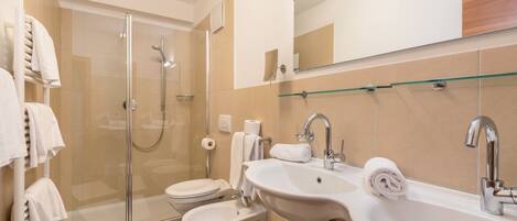 Une salle de bain moderne avec une douche à parois de verre, deux lavabos, des toilettes et un miroir.