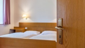 A hotel room with a wooden headboard, a bedside table, and a lamp.