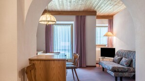 A cozy room with a wooden dining table, chairs, a sofa, a TV, and a lamp.