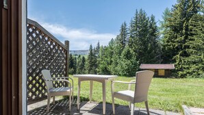 An outdoor patio with wicker furniture and a view of a forested area.