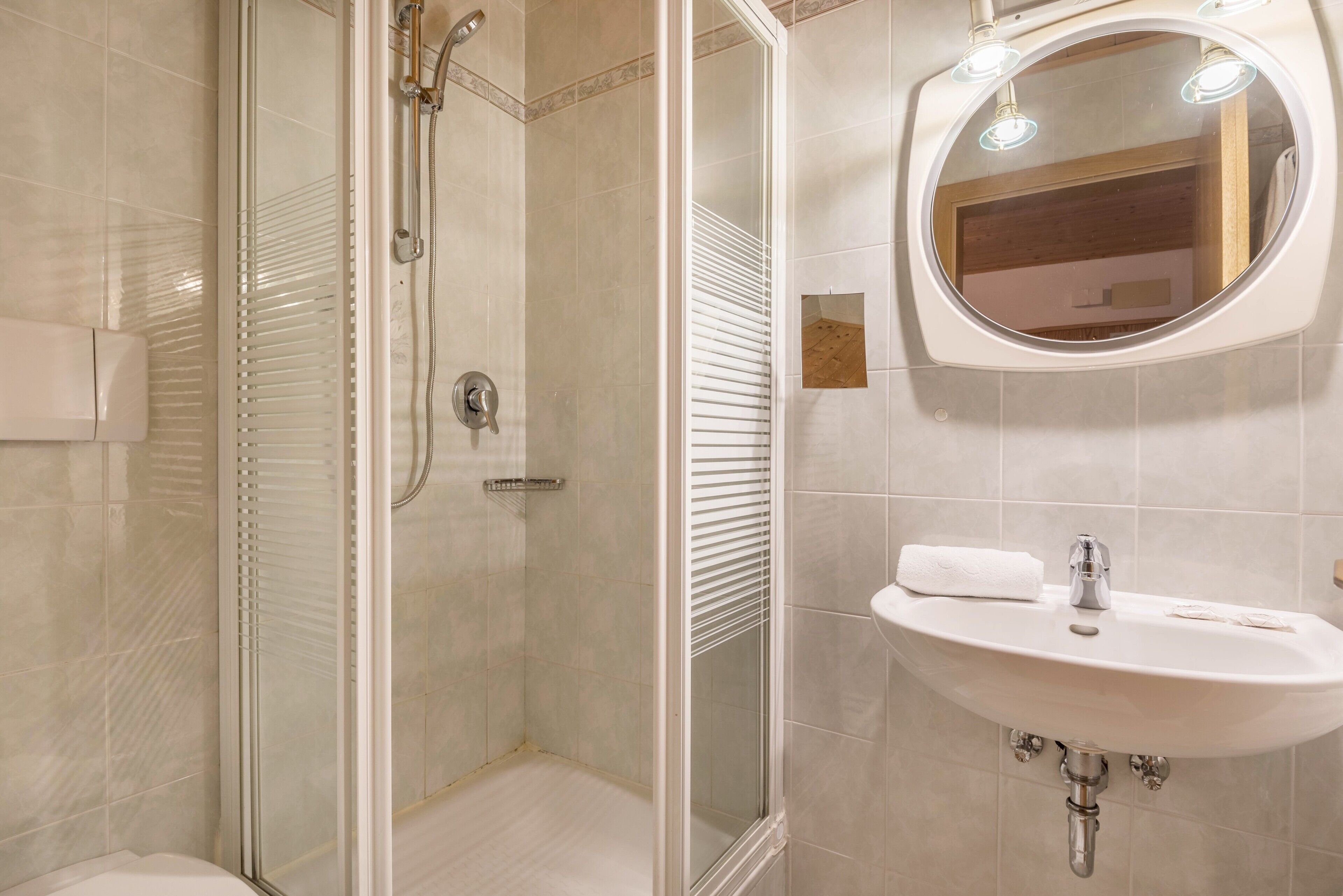 Een badkamer met een douche met glazen wand, een wastafel met spiegel en een handdoek.