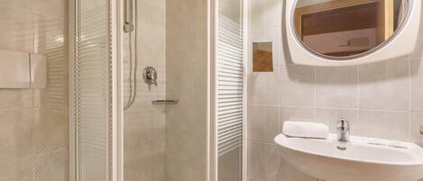 Een badkamer met een douche met glazen wand, een wastafel met spiegel en een handdoek.