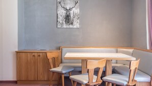Un coin salon avec une table et des chaises en bois, un banc et une œuvre d’art représentant un cerf, accrochée au mur.