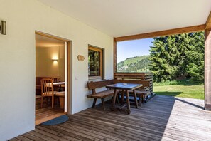 A wooden deck with a table and chairs, a bench, and a view of a green landscape. - Holiday Apartment "Ferienparadies Sabina Piz" in the Nature Park Next to Seiser Alm (Castelrotto / Alpe di Siusi)