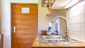 A kitchen with a wooden door, a stainless steel sink, and a coffee machine. - Holiday Apartment "Ferienparadies Sabina Piz" in the Nature Park Next to Seiser Alm (Castelrotto / Alpe di Siusi)