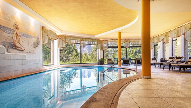 A swimming pool with a mural, sun loungers, and a view of trees. - Holiday Apartment "Ferienparadies Sabina Piz" in the Nature Park Next to Seiser Alm (Castelrotto / Alpe di Siusi)