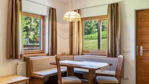 A room with a wooden table, bench seating, and two windows with curtains. - Holiday Apartment "Ferienparadies Sabina Piz" in the Nature Park Next to Seiser Alm (Castelrotto / Alpe di Siusi)