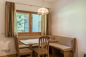 A room with a window, a table, a bench, and a hanging light fixture.