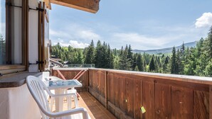 A balcony with a wooden railing, a table, and two chairs.