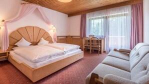 A room with a wooden bed, a wooden headboard, a wooden chair, and a wooden sofa.