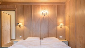 Una cama doble con dos mesitas de noche, paredes de paneles de madera y lámparas de pared.