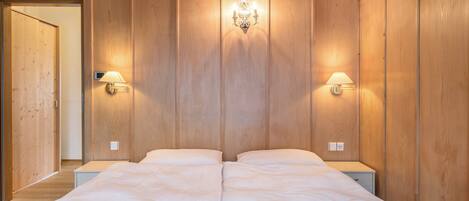 Una cama doble con dos mesitas de noche, paredes de paneles de madera y lámparas de pared.