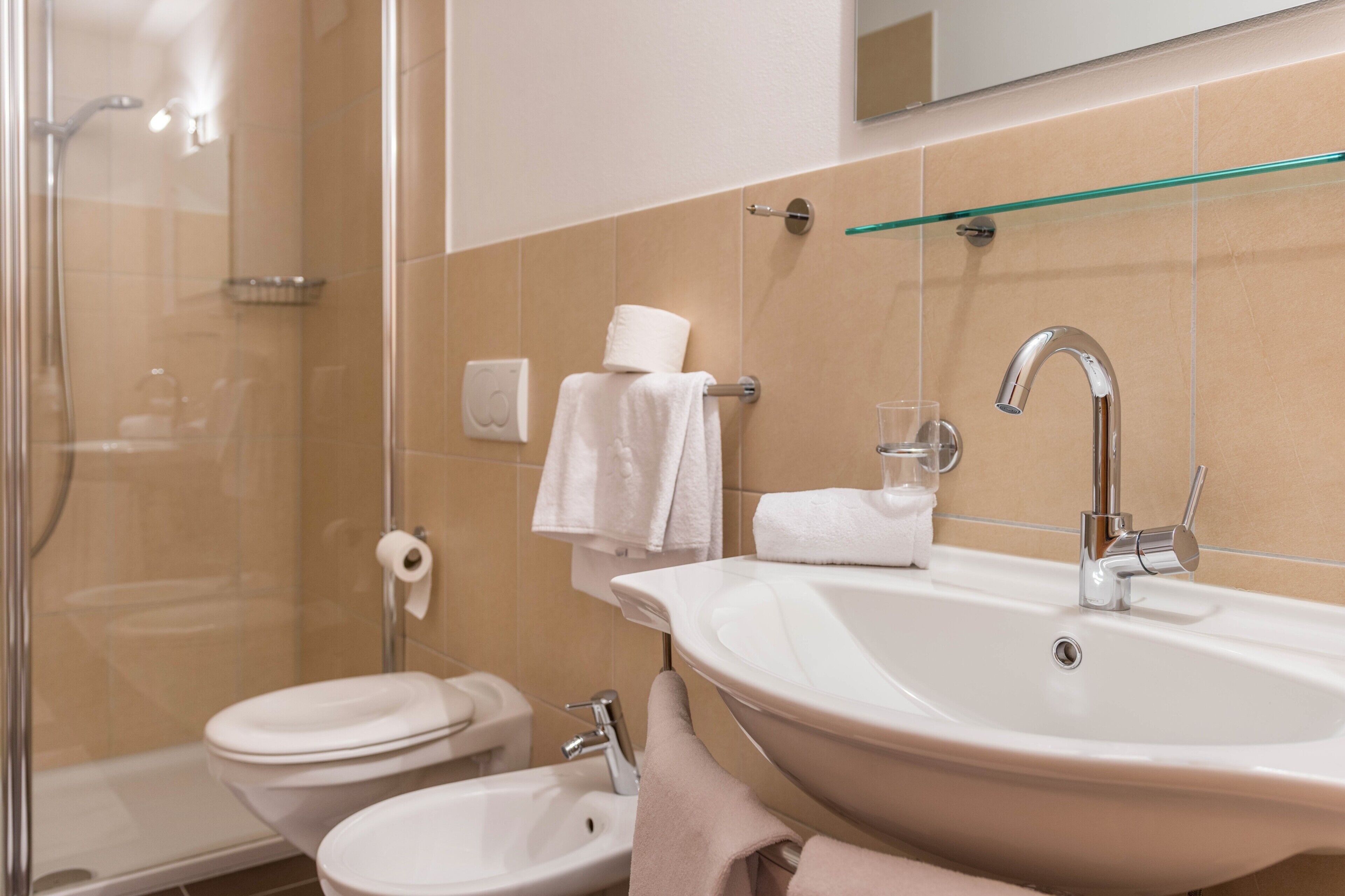 A bathroom with a shower, toilet, sink, and glass shower enclosure.