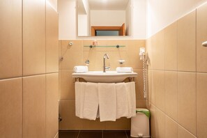 Ein Badezimmer mit Waschbecken, Spiegel, Handtuchhalter und Toilette.