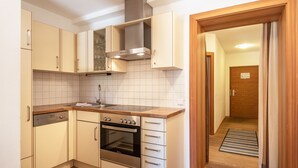 Cocina compacta con lavavajillas, horno y encimera de madera.