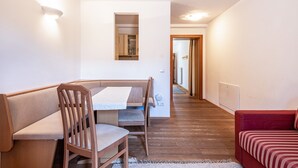Un comedor con una mesa y sillas de madera, un sofá rojo y un pasillo que lleva a la cocina.