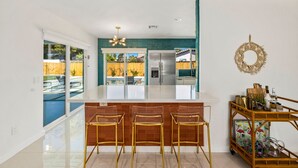 Una cocina moderna con una isla central, electrodomésticos de acero inoxidable y una barra de vidrio transparente con taburetes.