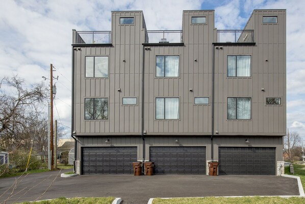 A modern multi-story building with a flat roof, large windows, and a garage. - Modern & Stylish Townhome with Cozy Rooftop (Nashville)