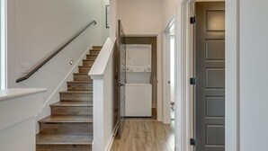 Un escalier menant à une buanderie équipée d’un lave-linge et d’un sèche-linge.