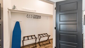 Un couloir avec un mur blanc, une planche de surf bleue et deux bancs en bois.