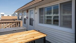Un bâtiment d’un seul étage doté d’une terrasse en bois, d’une fenêtre avec des stores et d’une porte portant l’inscription « 308 ».