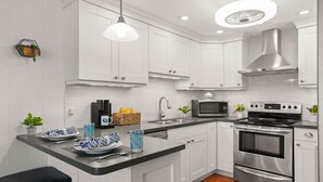Une cuisine moderne avec des meubles blancs, une cuisinière en acier inoxydable, un four à micro-ondes et un évier.