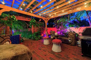 At night, the patio glows with soft ambient lighting and gentle shadows from lush greenery. String lights create a cozy, romantic atmosphere—perfect for evening cocktails, quiet conversations, or unwinding under the stars in total privacy. - Magical Manatee Waterfront Cove | Near IRB (Largo)