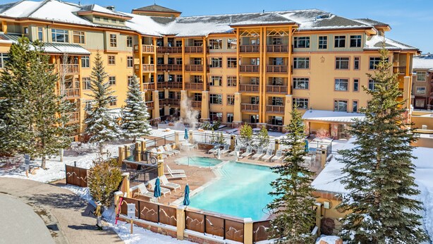 Un hotel de varios pisos con piscina, zona de estar al aire libre y paisajes nevados.