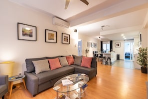 A modern living room with a grey sectional sofa, a glass coffee table, and a dining area in the background. - Apartment 'Casa Malaga' with Terrace, A/C & Wi-Fi (Málaga)
