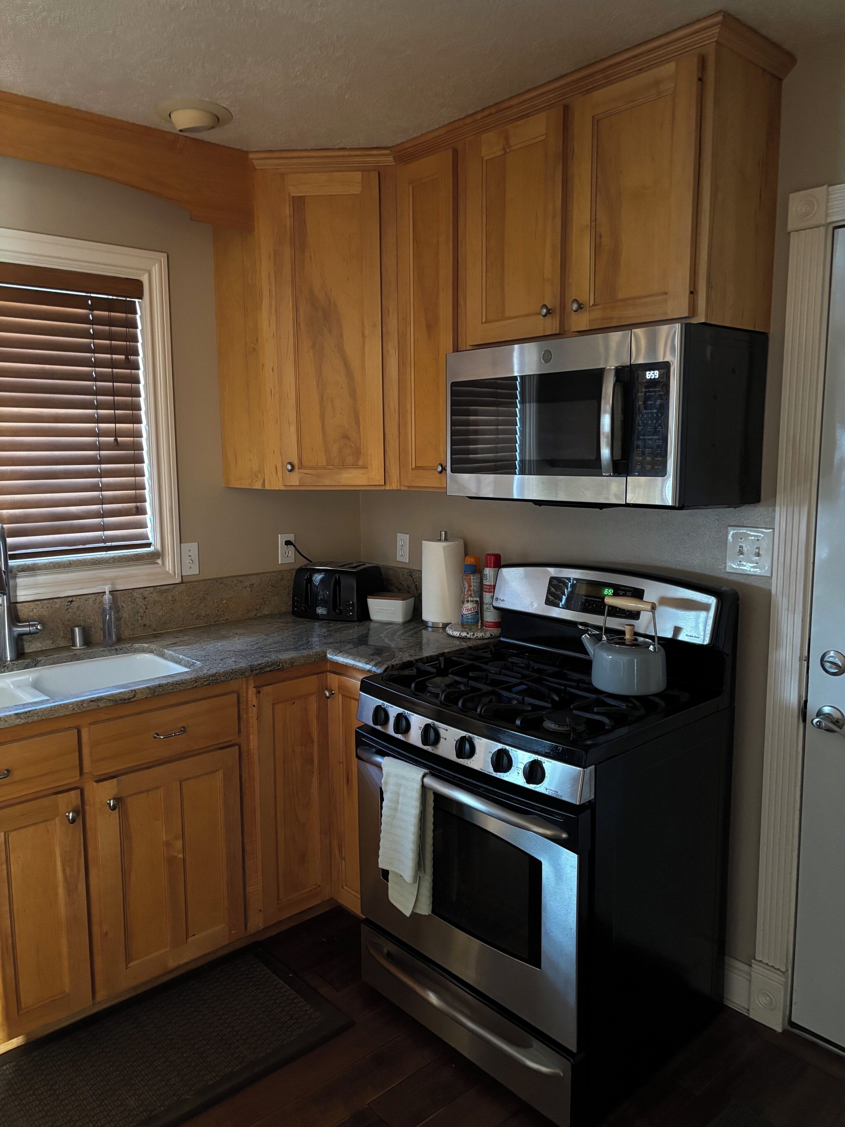 A kitchen with wooden cabinets, a stainless steel stove, a microwave, and a toaster.