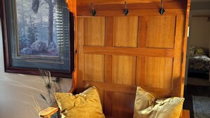 Een houten bank met twee kussens, een lijst met daarop een afbeelding van een adelaar, en een bord met de tekst 'dankbaar'.