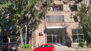 A red car parked in front of a building with a large glass entrance and a staircase leading up to the entrance. - Luxury2BED1Bath/central Yerevan Wi-Fi/2nd Floor/Demrtchyan40./ARMTRAVElTURE.com (YEREVAN)