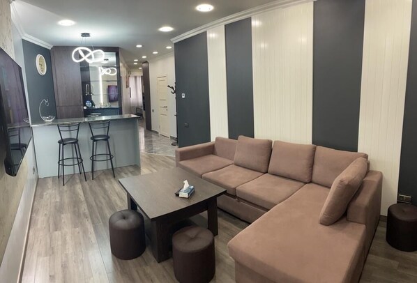 A modern living room with a beige sofa, a wooden coffee table, and a bar area with stools. - Luxury2BED1Bath/central Yerevan Wi-Fi/2nd Floor/Demrtchyan40./ARMTRAVElTURE.com (YEREVAN)