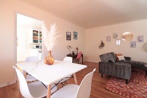 Un salón moderno con una mesa de comedor blanca, sillas blancas, un sofá gris y una alfombra estampada.
