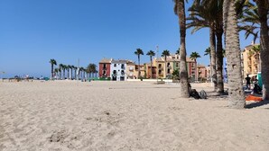 Una playa con palmeras y edificios coloridos al fondo.