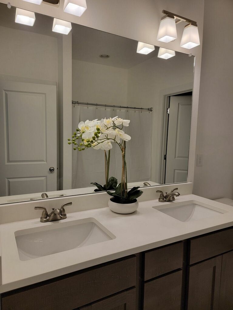 Een badkamer met twee wastafels, een grote spiegel en een potorkidee.