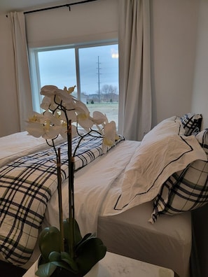 A bedroom with two beds, a window with curtains, and a potted orchid. - Cozy New Townhome - W/Fireplace Quiet Neighbors (West Des Moines)
