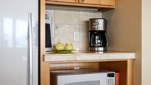 Una cocina con un refrigerador blanco, un microondas y una cafetera sobre la encimera.