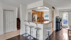 A kitchen with a central island, wooden cabinets, and a stainless steel refrigerator.