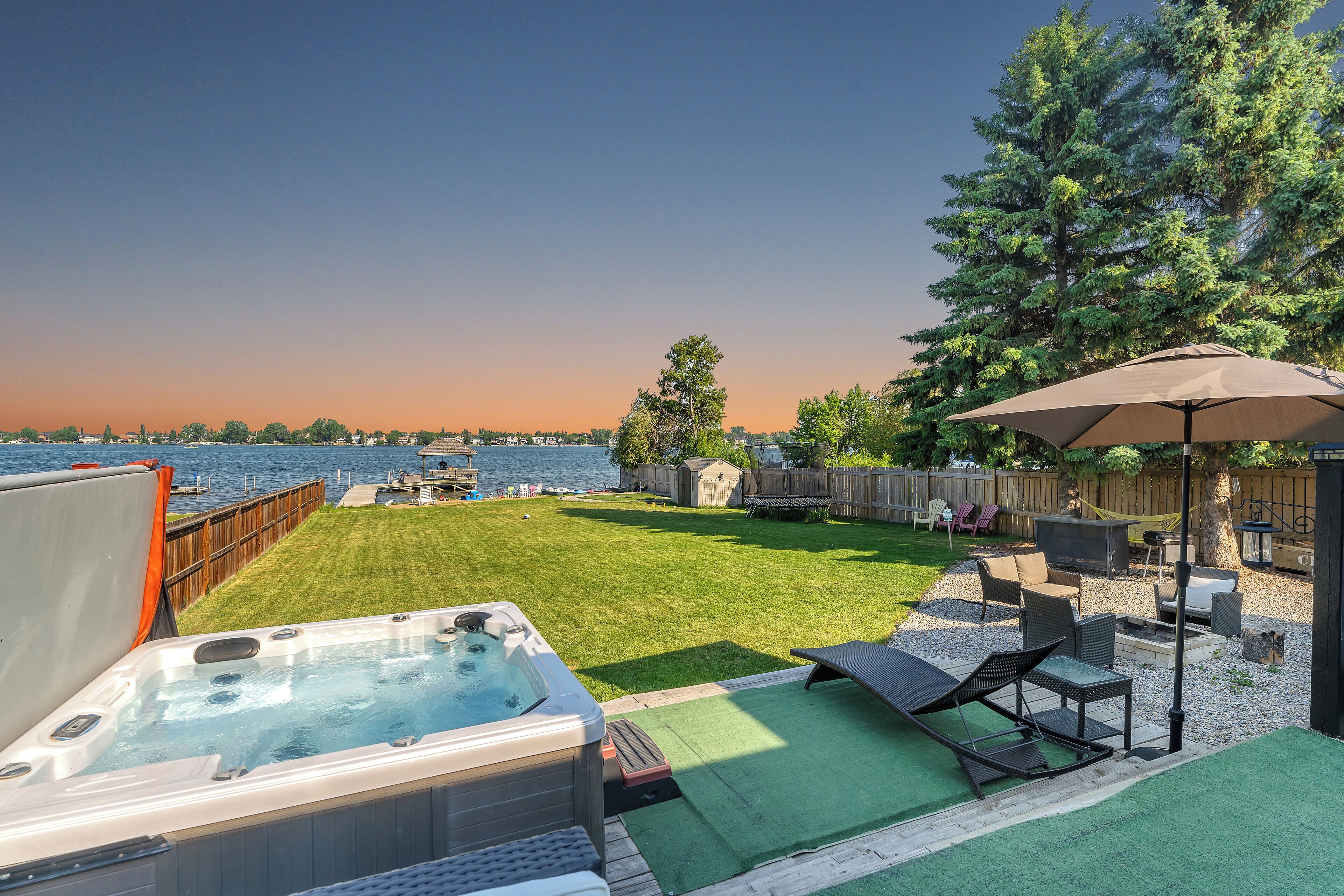 Un jardin avec un jacuzzi, des meubles de patio et une vue sur l’eau.