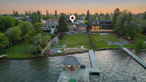 A lakeside property with a dock, a grassy yard, and a house in the background.