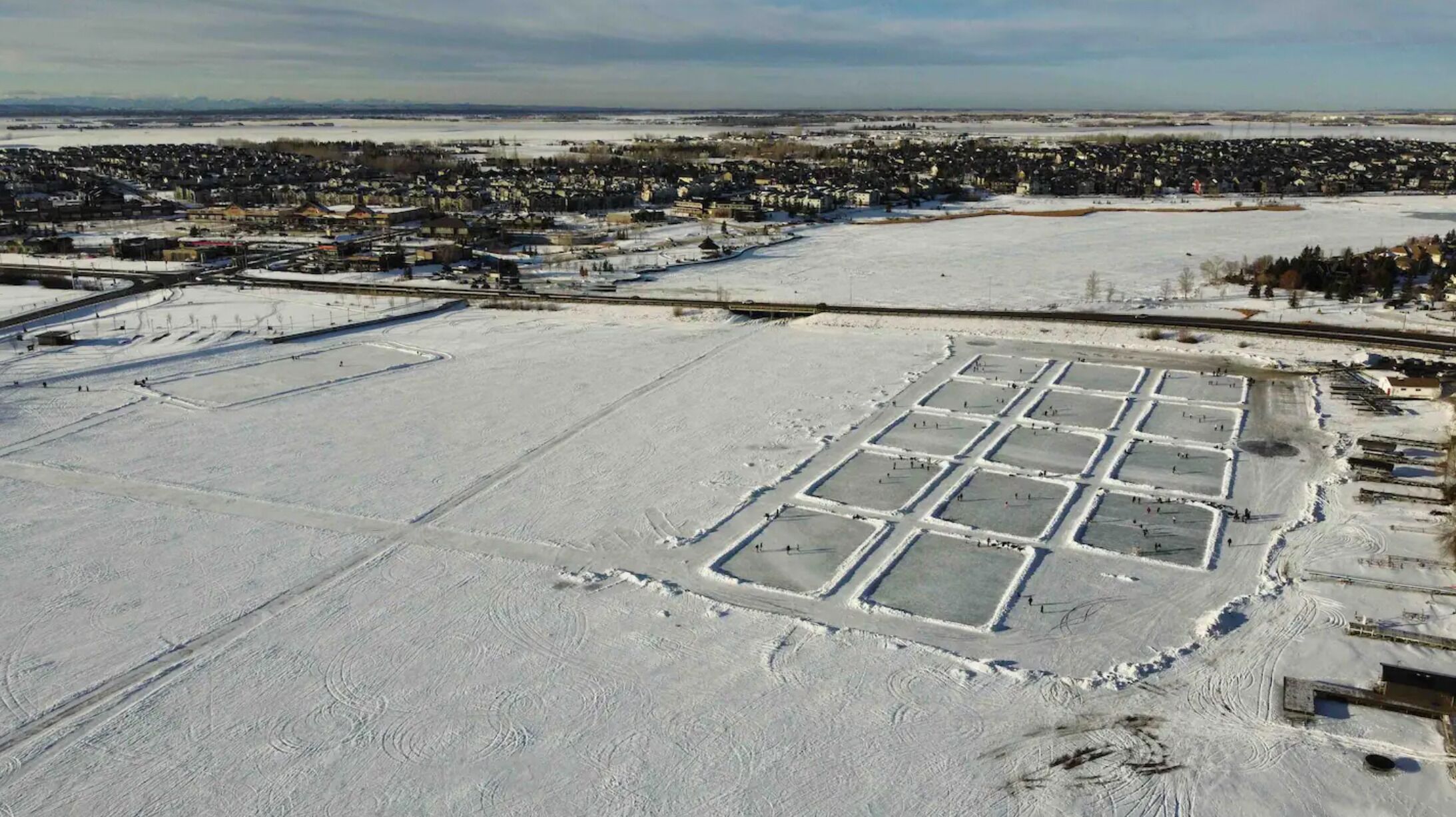 A large, open, snow-covered area with rectangular sections, possibly for sports or events.
