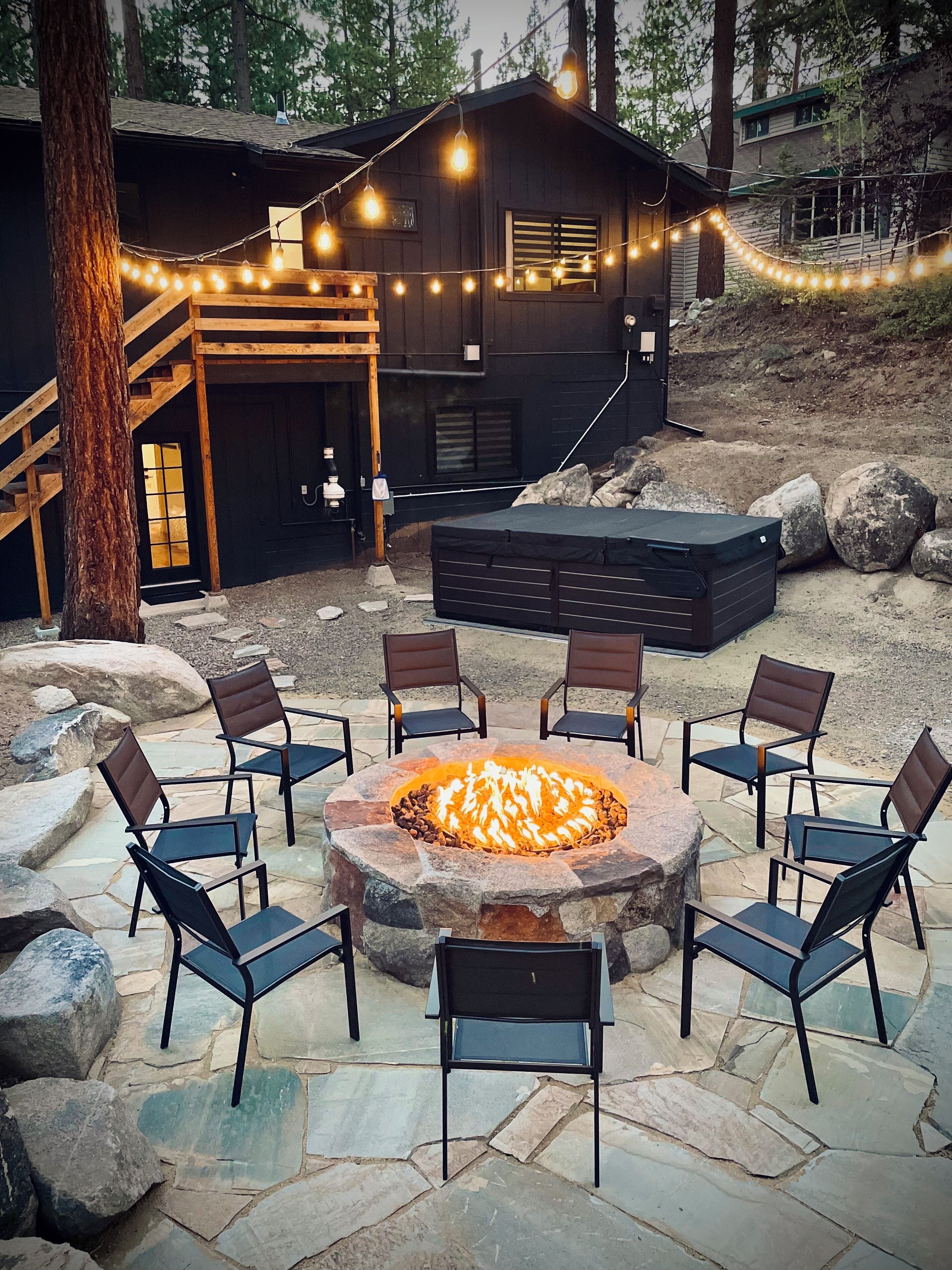 Backyard with fire-pit, hot tub, and string lights on the edge of the forest
