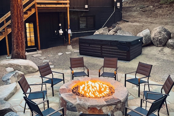 Backyard with fire-pit, hot tub, and string lights on the edge of the forest